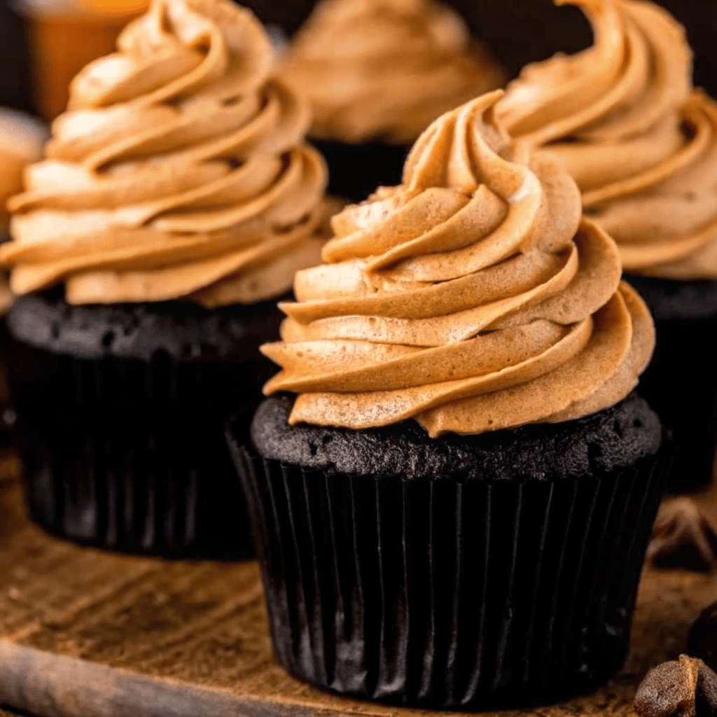 Rich chocolate pumpkin cupcakes topped with swirled pumpkin cream cheese frosting, garnished with a sprinkle of cinnamon