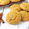 Stack of golden-brown pumpkin sugar cookies on a white plate, showing their soft, thick texture and perfect autumn color